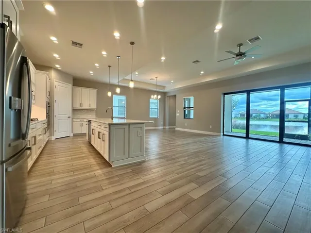 Kitchen featuring a center island with sink, white cabinetry, stainless steel fridge with ice dispenser, and light hardwood / wood-style flooring