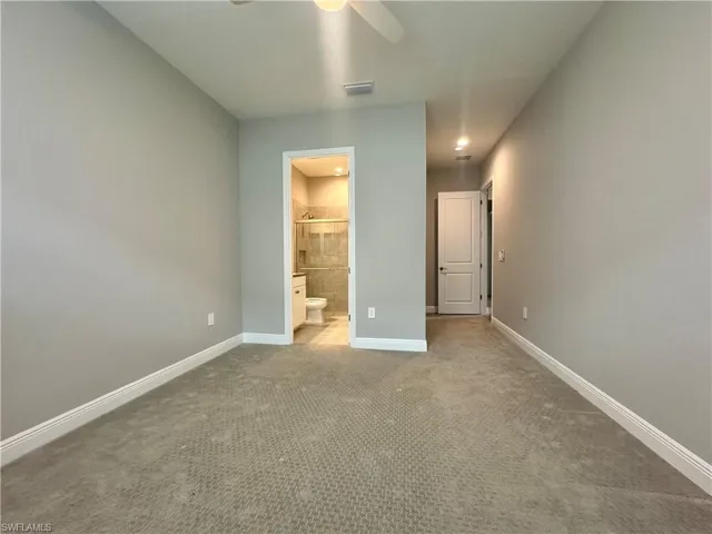 Unfurnished bedroom featuring ceiling fan, carpet floors, and ensuite bath
