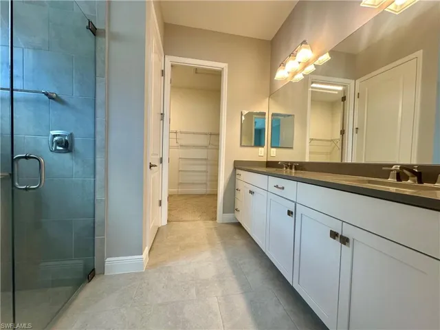 Bathroom featuring vanity, tile patterned floors, and a shower with door