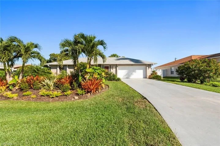 Ranch-style house with a front lawn, a garage, concrete driveway, and stucco siding
