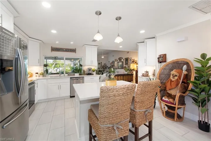 Kitchen featuring appliances with stainless steel finishes, pendant lighting, white cabinets, backsplash, and a kitchen breakfast bar