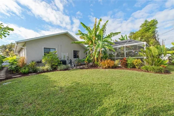Back of property with a lanai, stucco siding, a yard, and a sunroom