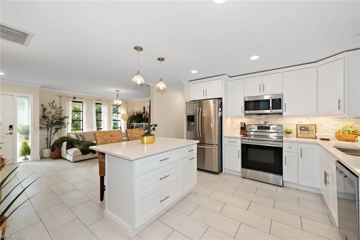 Kitchen featuring appliances with stainless steel finishes, white cabinetry, a breakfast bar area, ornamental molding, and recessed lighting
