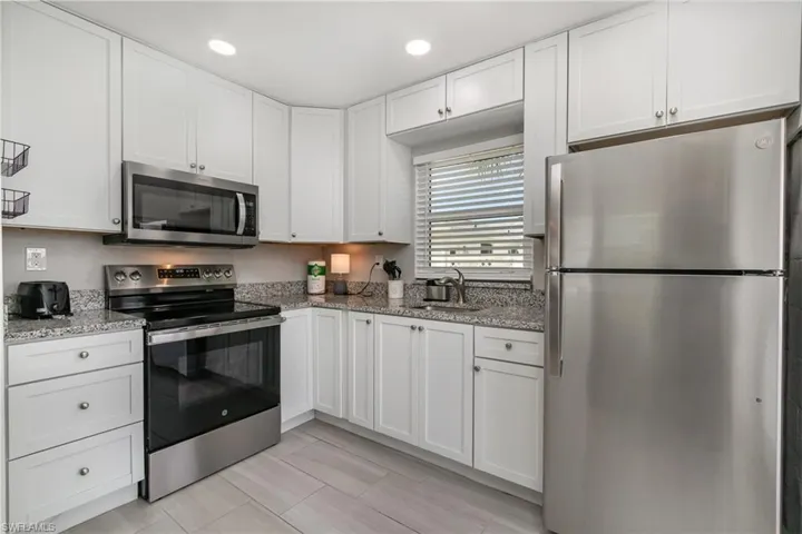 Kitchen features white shaker-style cabinetry and granite counters!