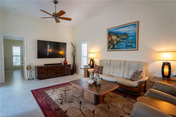 Living room with a healthy amount of sunlight, light tile patterned flooring, and lofted ceiling