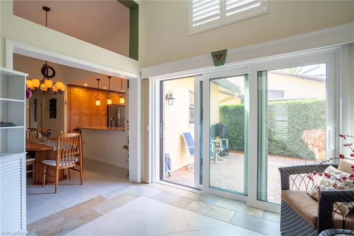 Doorway to outside featuring light tile patterned floors, a high ceiling, and an inviting chandelier