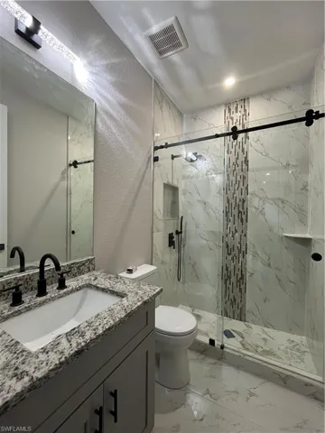 Bathroom with vanity, toilet, and an enclosed shower