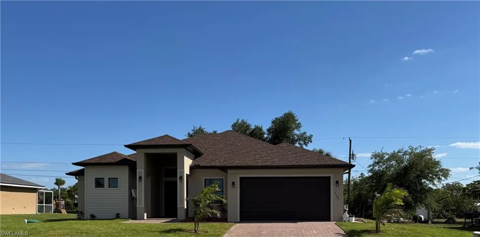 View of front of house featuring a front lawn, roof with shingles, decorative driveway, and a garage
