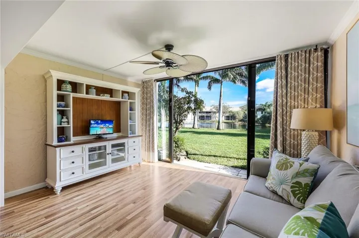 Living room featuring ceiling fan, expansive windows, crown molding, and light hardwood / wood-style flooring