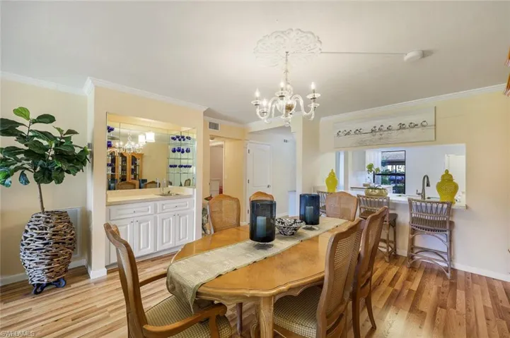 Dining room with crown molding, light hardwood / wood-style flooring, and an inviting chandelier
