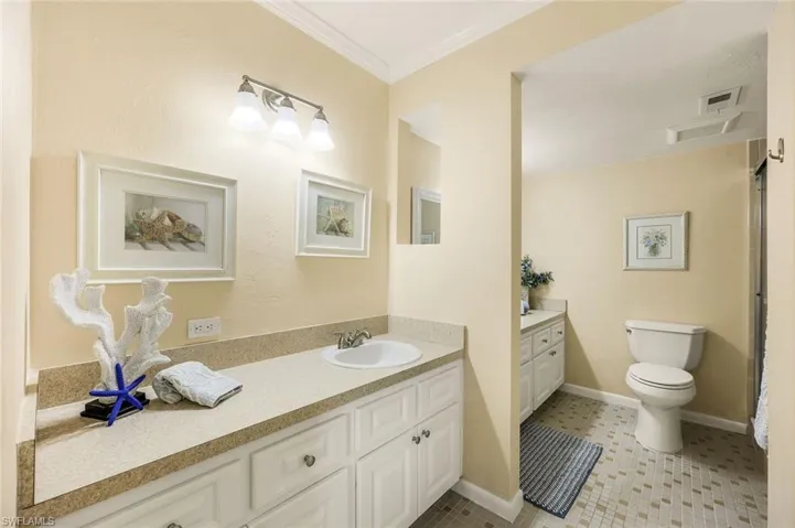 Bathroom with tile patterned flooring, vanity, toilet, and ornamental molding