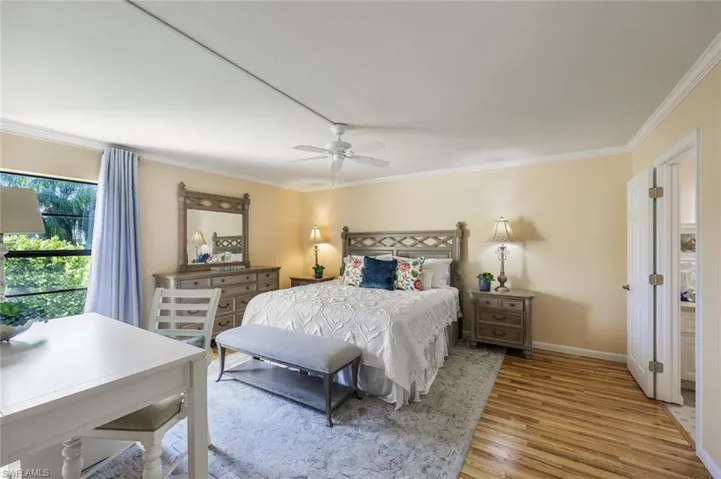Bedroom with hardwood / wood-style floors, ceiling fan, and crown molding
