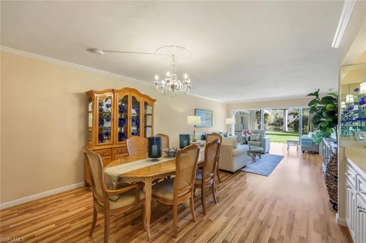 Dining area featuring light wood-type flooring, ornamental molding, and an inviting chandelier