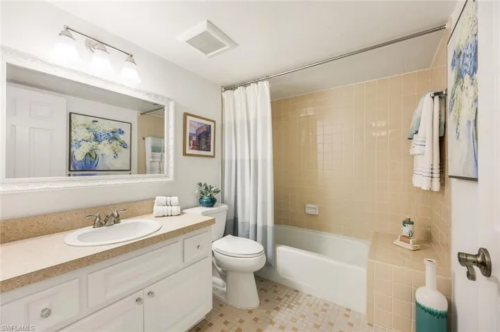 Full bathroom featuring tile patterned flooring, shower / bath combination with curtain, toilet, and vanity