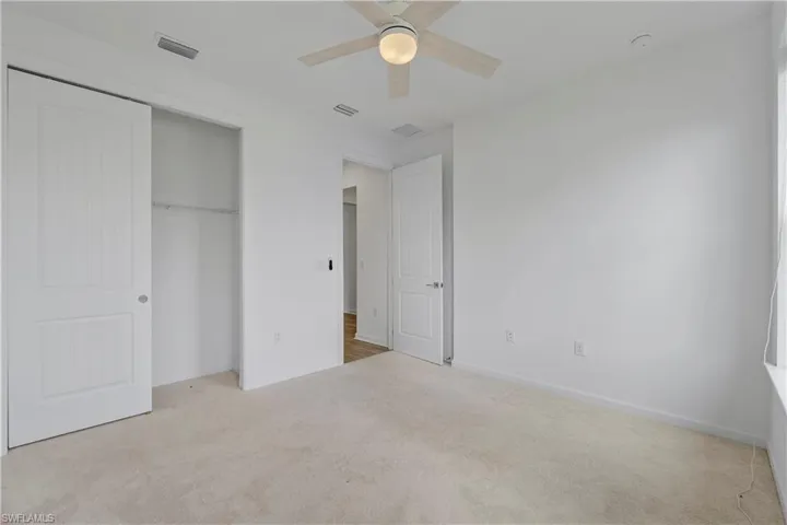 Wall-to-wall carpeting, ceiling fan with integrated lighting, paneled interior doors, and a built-in closet system