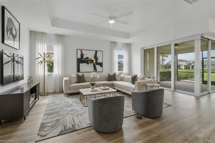 Tray ceiling featuring a ceiling fan, wood-finish flooring, and expansive sliding glass doors