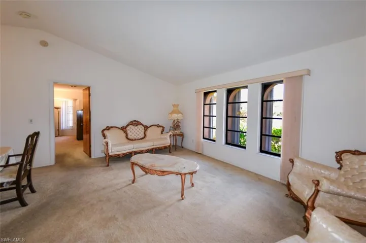Living area featuring vaulted ceiling and light colored carpet