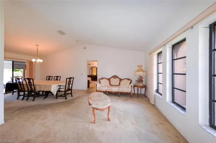 Carpeted dining area with an inviting chandelier and vaulted ceiling