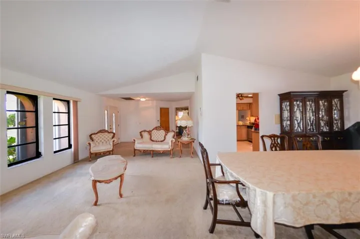 Dining space with lofted ceiling and light colored carpet