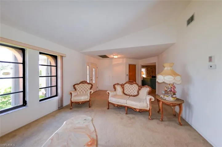 Sitting room with lofted ceiling and light colored carpet