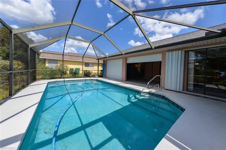View of pool featuring a patio area and glass enclosure