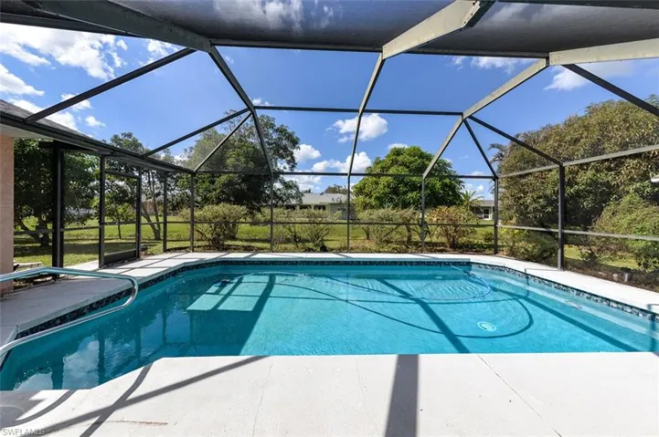 View of pool featuring a patio area and glass enclosure