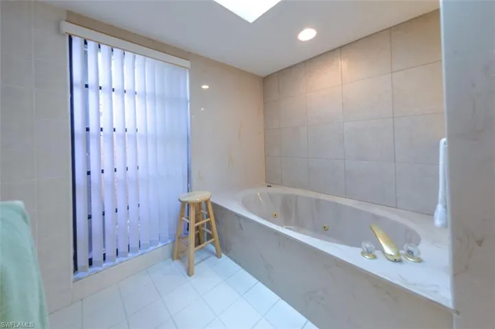 Bathroom with tile patterned floors, tiled tub, and tile walls