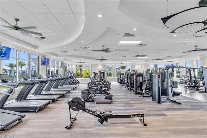 Workout area with a ceiling fan, a raised ceiling, a drop ceiling, and recessed lighting