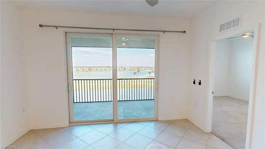 Empty room with ceiling fan, healthy amount of natural light, a water view, and light tile patterned flooring