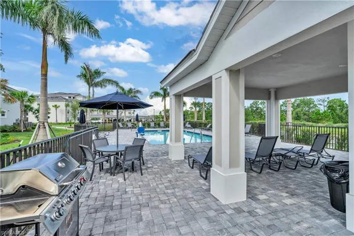 View of patio featuring a grill, a community pool, and outdoor dining area