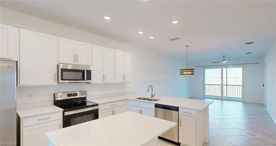 Kitchen featuring stainless steel appliances, white cabinetry, open floor plan, and a ceiling fan