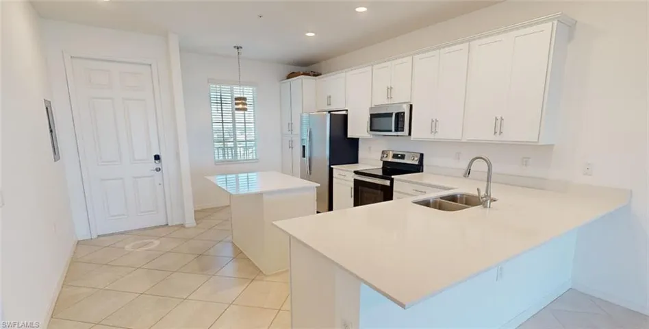 Kitchen with a kitchen island, white cabinetry, stainless steel appliances, a peninsula, and recessed lighting
