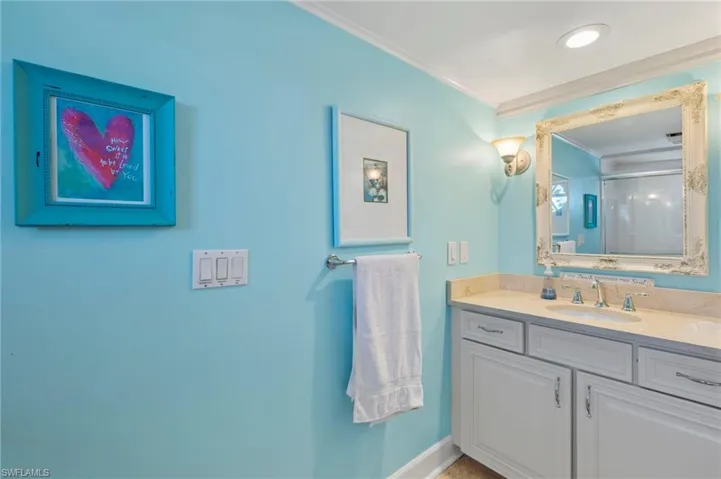 Full bathroom with vanity, a shower with shower door, and ornamental molding