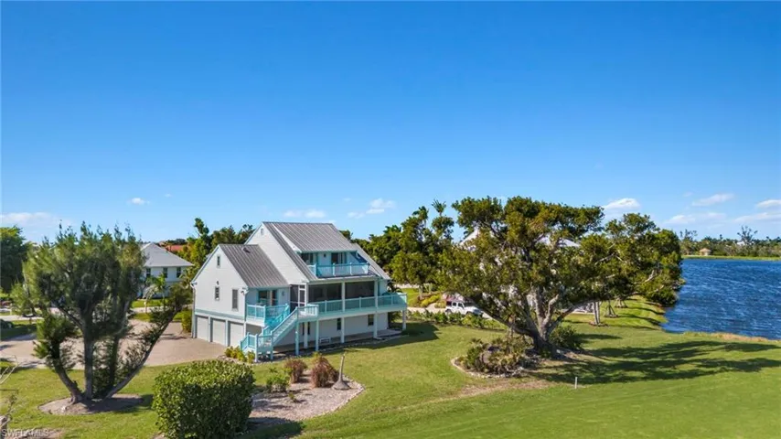 Rear view of house featuring a lawn, a metal roof, a garage, and a water view