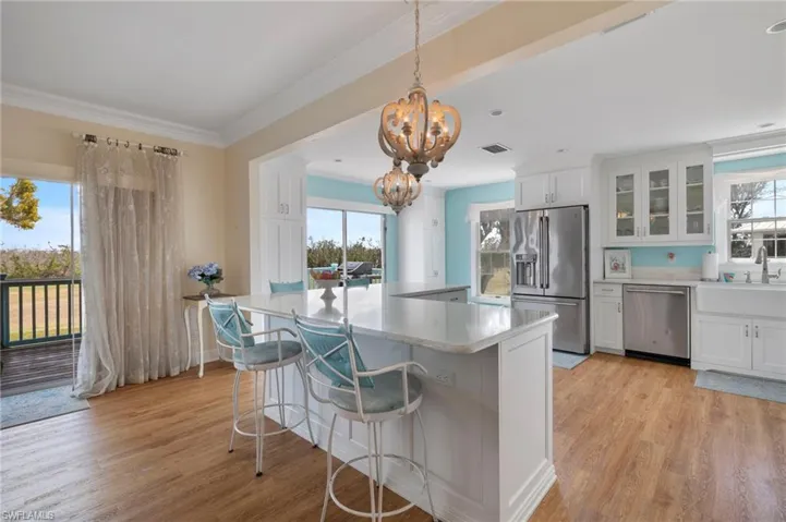 Kitchen featuring white cabinets, appliances with stainless steel finishes, glass insert cabinets, light wood-style flooring, and crown molding