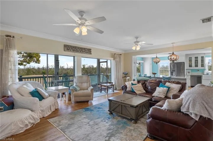Living room with crown molding, wood finished floors, and a ceiling fan