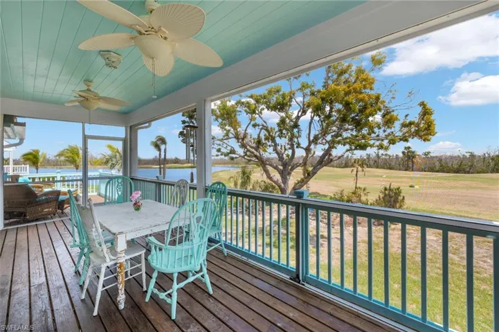 Wooden terrace with a ceiling fan, a lawn, outdoor dining space, and a sunroom