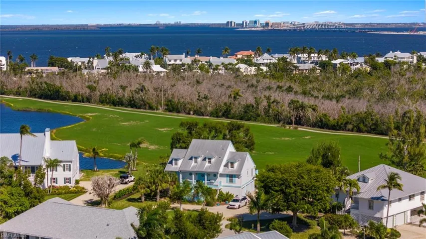 Aerial perspective of suburban area featuring a nearby body of water and a golf club