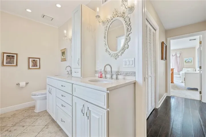Ensuite bathroom with a closet, double vanity, ornamental molding, and recessed lighting