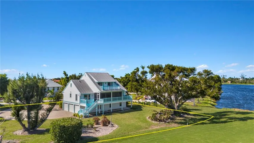 Rear view of property with a lawn, a metal roof, a garage, a water view, and a balcony