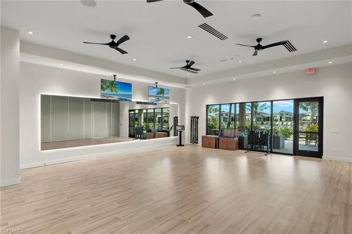 Exercise room featuring light wood-type flooring, recessed lighting, a high ceiling, and a tray ceiling