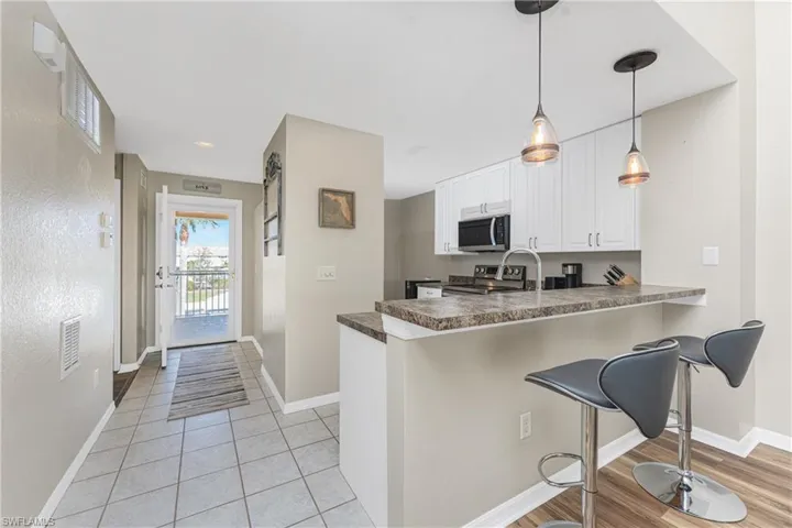 Kitchen with pendant lighting, white cabinets, a kitchen bar, kitchen peninsula, and stainless steel appliances
