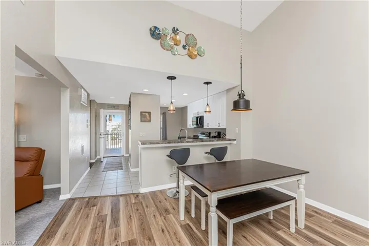 Dining room featuring high vaulted ceiling, sink, and light wood-type flooring