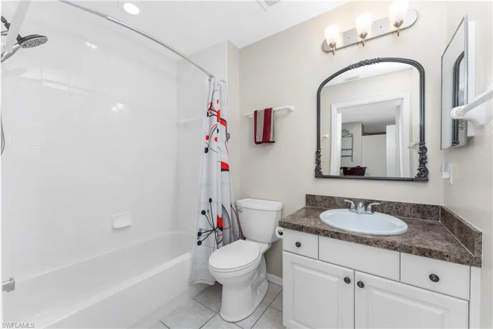 Full bathroom with vanity, shower / tub combo, tile patterned floors, and toilet