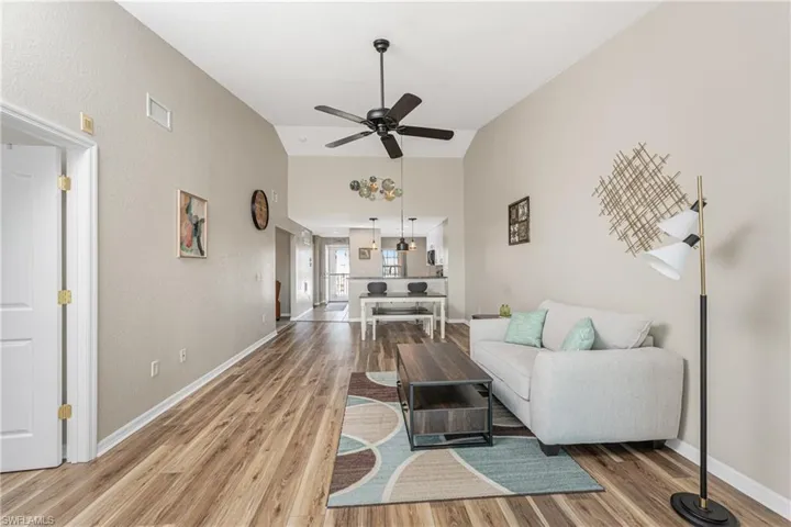 Living room with ceiling fan, wood-type flooring, and lofted ceiling