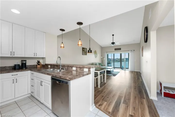 Kitchen featuring sink, dishwasher, kitchen peninsula, pendant lighting, and white cabinets