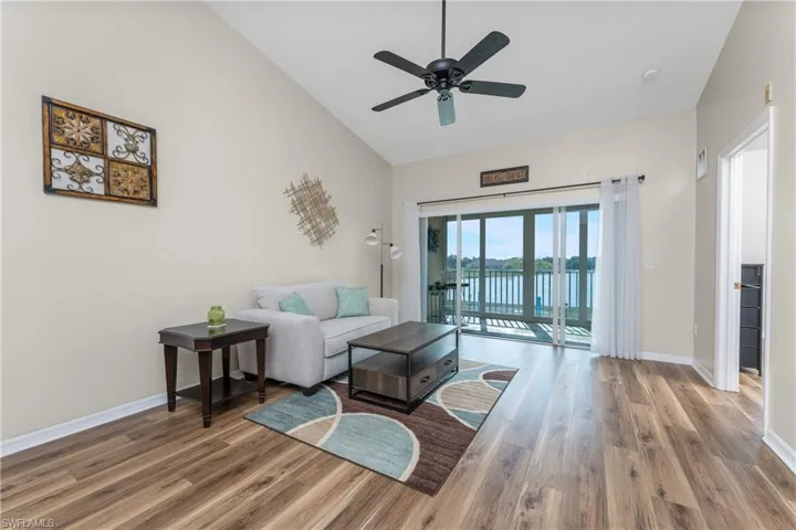 Living room with hardwood / wood-style flooring, high vaulted ceiling, and ceiling fan