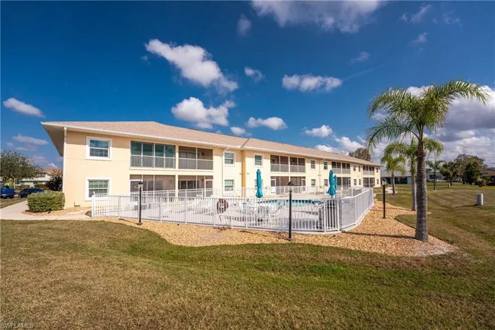 Rear view of property with a community pool and a lawn