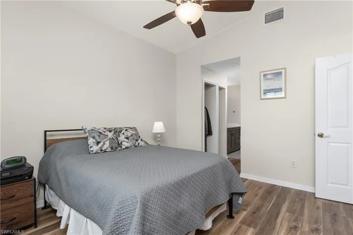 Bedroom featuring dark wood-type flooring, ceiling fan, lofted ceiling, and connected bathroom
