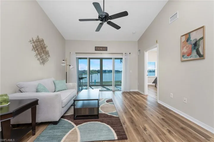 Living room with hardwood / wood-style floors, vaulted ceiling, and ceiling fan